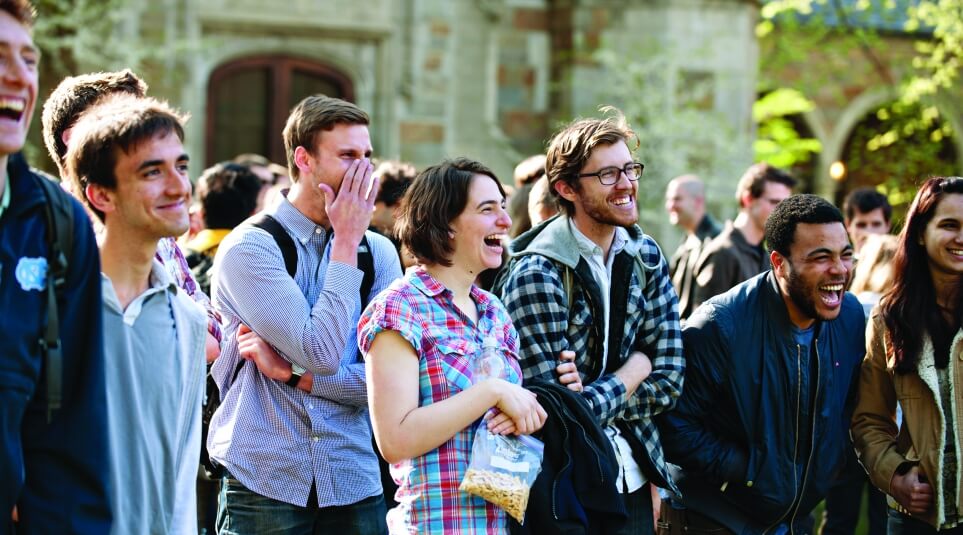 A group of diverse students laughing outside on the quad